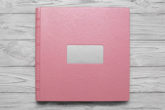 pink photobook with  leather jacket cover and shield
photoalbum with a hard cover on a wooden surface