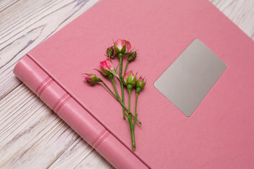 pink photobook with  leather jacket cover and shield
photoalbum with a hard cover on a wooden surface