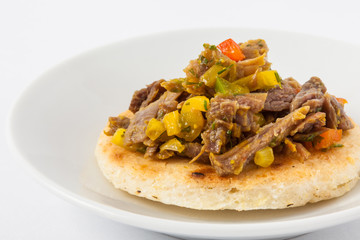 Traditional Colombian arepa topped with shredded beef