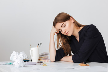 Photo of cute lady sitting at the white desk and sleeping while leaning head on her hand isolated