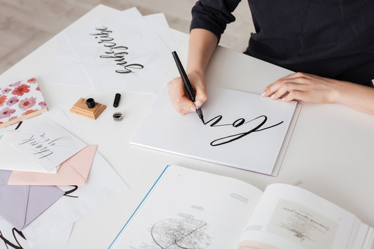 Photo of young woman hands writing beautiful notes on paper with open book on desk isolated