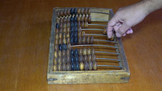 Old wooden abacus. A person does a mathematical or accounting calculation.