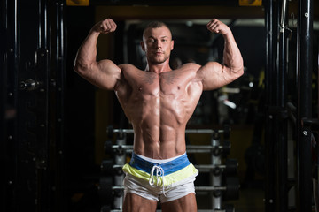 Fototapeta na wymiar Bodybuilder Posing Biceps After Exercises