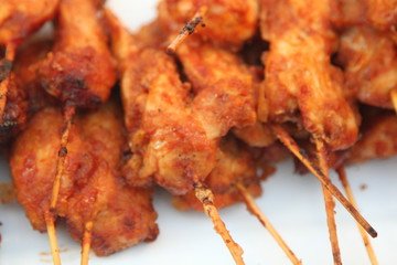 Skewered barbecued chicken strips on a tray with parchment