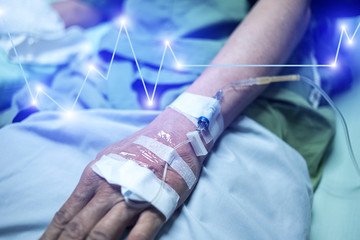 Hand of a patient in Hospital ward with Heart rate graphic, Patient Health Care concept.