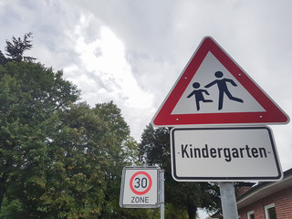 Verkehrsschilder mit Tempo 30 Zone verkehrsberuhigt und Hinweis auf Kindergarten und Kinder