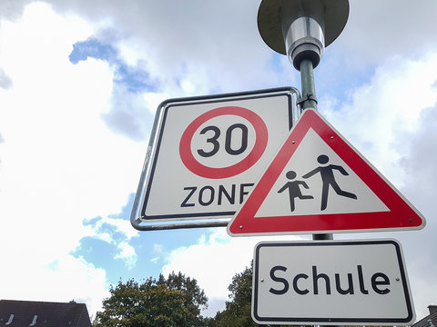 Verkehrsschilder mit Tempo 30 Zone verkehrsberuhigt und Hinweis auf Schule und Kinder