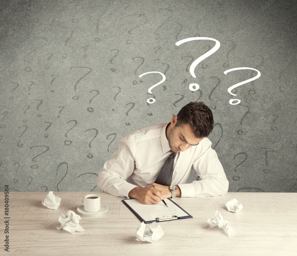 Wall mural Businessman at desk with question mark