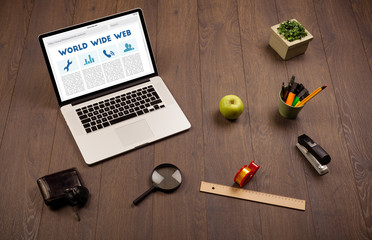 Laptop on wooden desk with office suplies