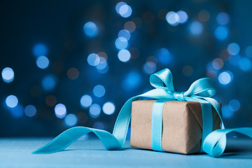 Christmas gift box or present with bow ribbon on magic blue bokeh background. Copy space for...