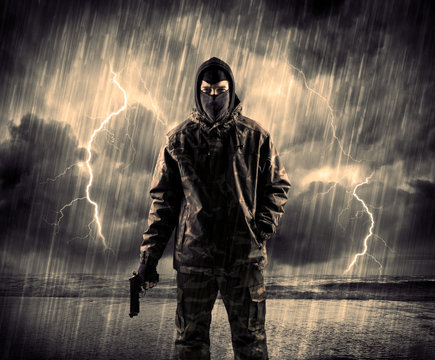 Dangerous armed terrorist with mask and gun in a thunderstorm with lightning