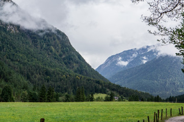 Beautiful landscape in Tirol Alps. mountains, green grass with fence and cloudy sky. Austria.