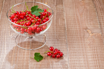 glass bowl full of red currant/glass bowl full of red currant on a wooden background. With copy space