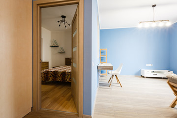 Royal blue wall in simple scandinavian dining room with wooden and white communal table chair