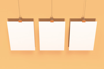 Three blank white posters with binder clip mockup on orange background