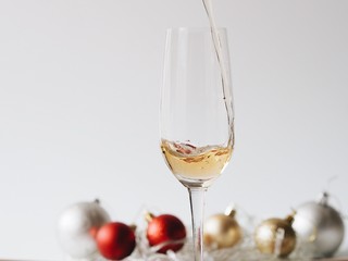 A glass of champagne with blurry Christmas decoration background.