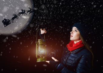Fototapeta premium Girl with lantern at Christmas night pointing the way for Santa Claus