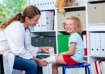 Obraz premium female doctor bandaging the leg from a of girl