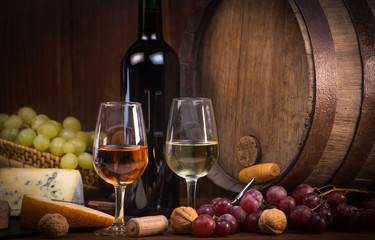 Glasses of rose and white wine cheeses grapesand barrel brown background © FreeProd