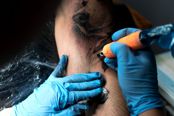Male tattooist making tattoo on shoulder, closeup