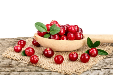 Cranberry with leaf in wooden spoon on old wooden table with white background