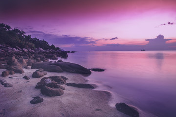 Fototapeta na wymiar beautiful bright purple pink sunset by the sea, stones on the sand. Stunning scenery