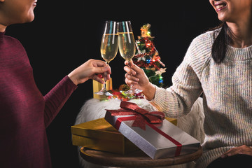 Beautiful two women holding glasses with champagne celebrating Christmas and gift boxes at corporate party, New Year Frame for your text