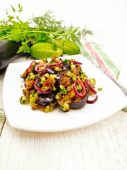 Salad from eggplant and cucumber with onion in plate on board