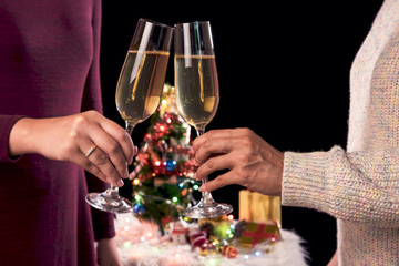Beautiful two women holding glasses with champagne celebrating Christmas and gift boxes at corporate party and christmas lights, New Year Frame for your text
