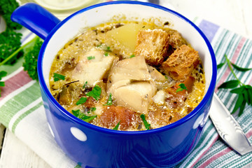 Soup fish with vegetables and herbs on light board