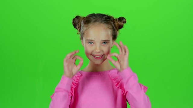 Child girl showing thumbs up and making faces. Green screen