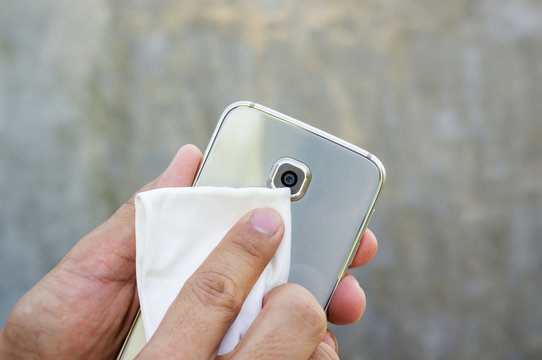 Man cleaning his smartphone with a microfiber cloth.