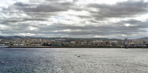 Fototapeta na wymiar Panoramic view of the city of La Coruna on the Atlantic coast of Galicia (Spain). Sky with dark clouds and sun reflections