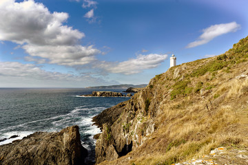 Fototapeta na wymiar View of Mera lighthouse on a cliff on the atlantic coast of Spain in La Coruña. Sky with clouds and sun facing