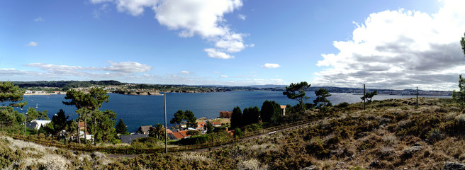 Panoramic view of the coast of La Coruna Bay with a blue sky and clouds receiving the reflection of the sun