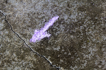 Colorful chalk drawing on asphalt: arrow pointing to the  crack wall. Shallow depth of field.