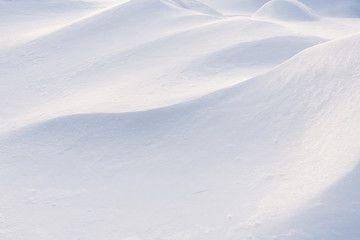 Play of light and shadow on undulating slopes of white snowdrifts.