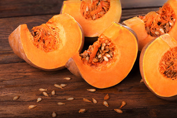 Pumpkin with seeds, cut into pieces on a wooden table. Healthy eating
