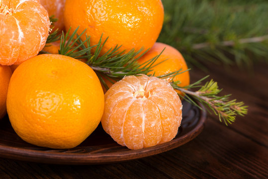 Tangerines in a bowl among fir branches.