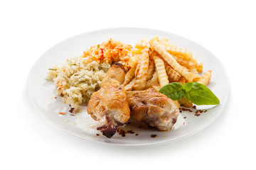 Grilled drumsticks with french fries and vegetables on white background