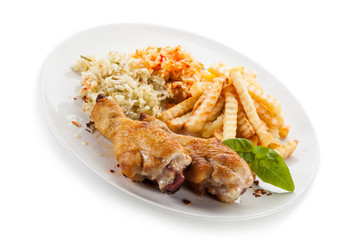Grilled drumsticks with french fries and vegetables on white background