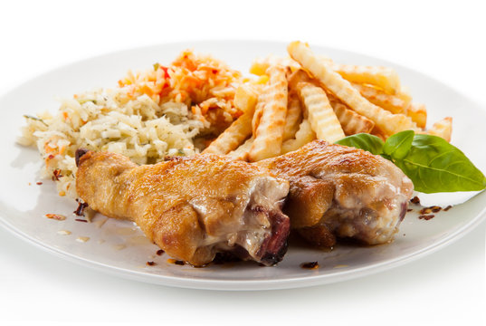 Grilled drumsticks with french fries and vegetables on white background