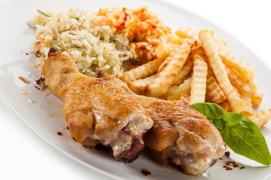Grilled drumsticks with french fries and vegetables on white background