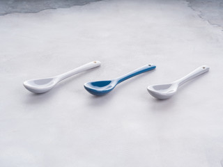 Three empty spoons with one different color in the middle on gray background. Diversity choice concept
