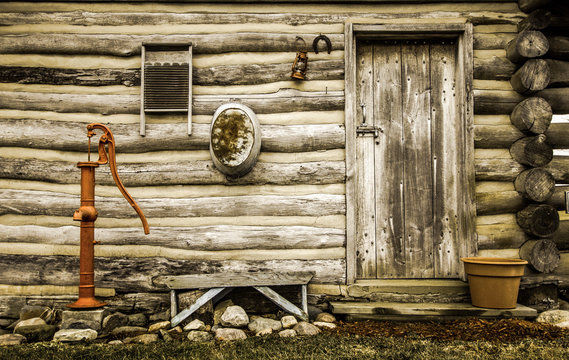 Rustic Log Cabin Exterior. Front door and exterior wall of a historical rustic log cabin with antique décor.