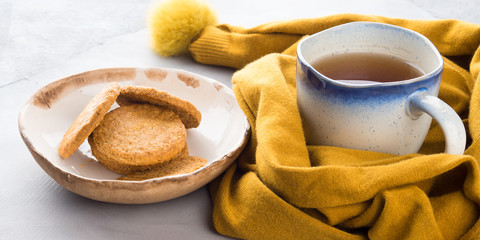 Winter comfort food concept with woman's scarf, mug of tea and cookies. Moment of relax