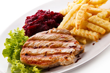 Grilled steak, French fries and vegetables on white background