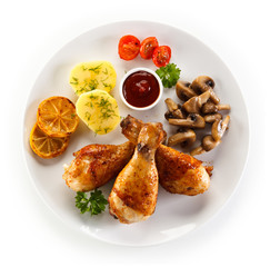Grilled chicken drumsticks with vegetables on white background