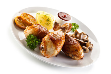 Grilled chicken drumsticks with vegetables on white background