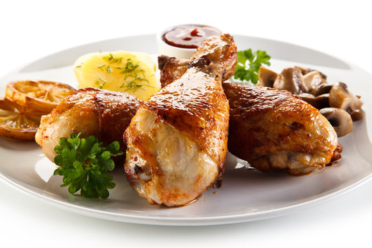 Grilled chicken drumsticks with vegetables on white background